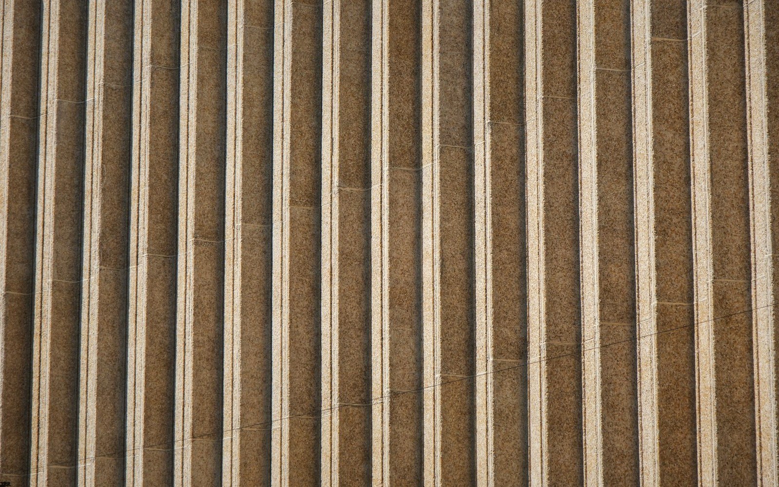 Close-up of vertical grooved stone columns showing parallel saw-cut ridges and shadowed channels